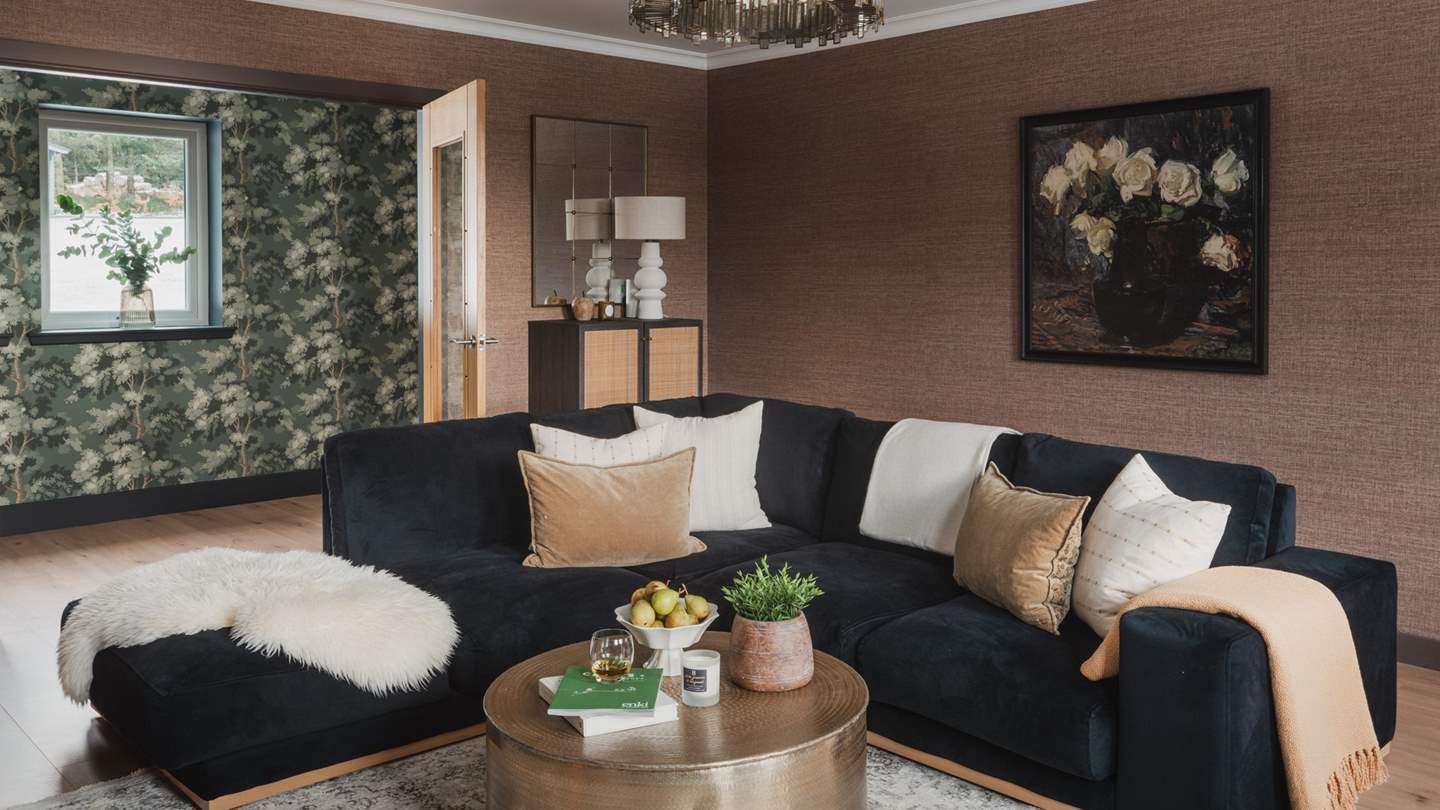 Inviting for movie night gatherings, you’ll find a black, L-shaped velvet sofa and a houndstooth armchair