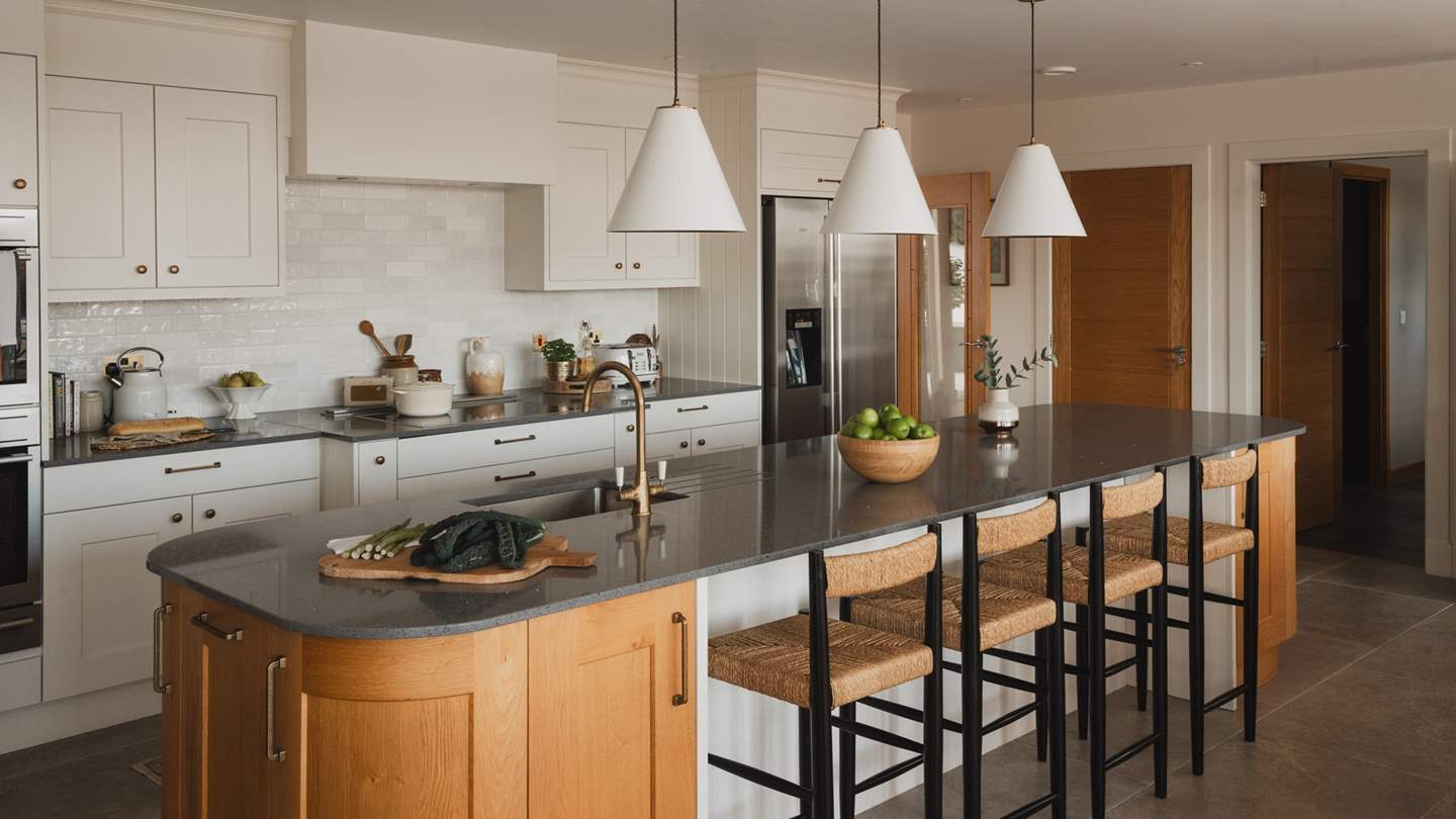 At the opposite end of this captivating space resides the solid wood kitchen, with a 5-metre long island and bespoke, white shaker cabinetry