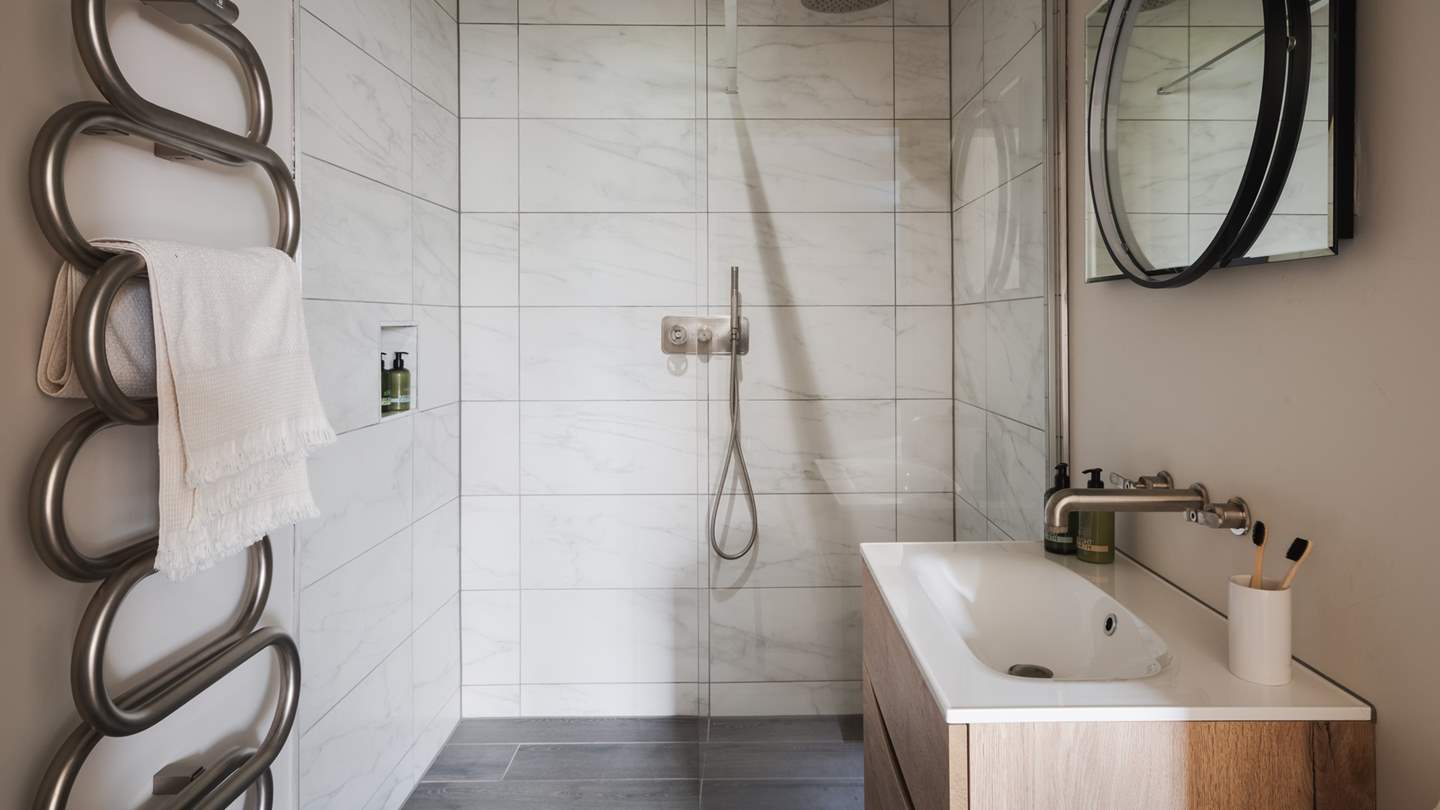Hidden behind a sliding door is the gorgeous en suite bathroom, with a shower and a heated rail