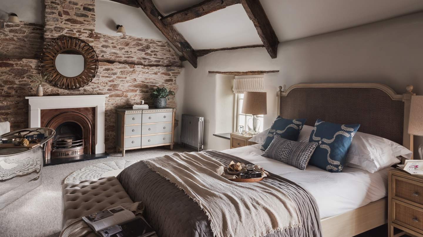 Uncover the sumptuous master bedroom, endlessly captivating with beautiful, vaulted ceilings with exposed beams and a stone feature wall