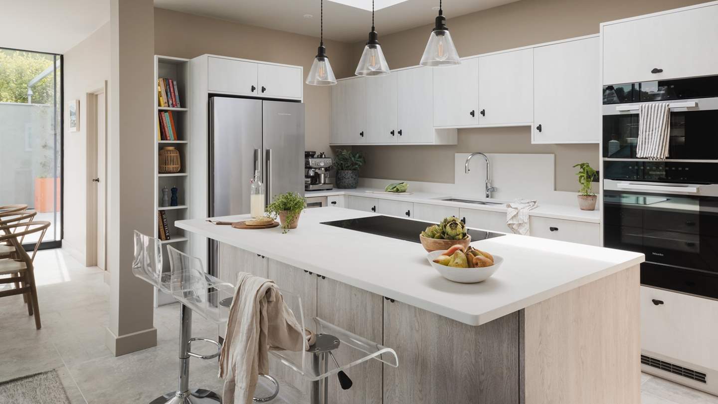 The spacious, air-conditioned kitchen, promising quartz countertops and a kitchen island set under a skylight, with contemporary Perspex breakfast stools and statement pendant lighting