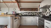 With Farrow & Ball white painted cabinets and black granite worktops, plus a full array of Cornishware