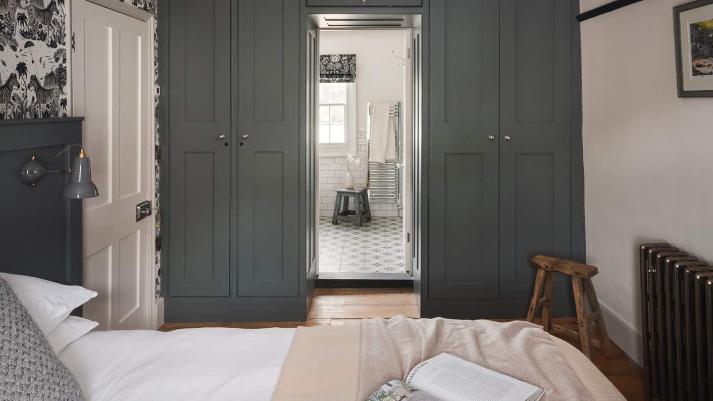Built-in wardrobes and an antique dressing table offer generous storage for treasures and complement the rich wood and forest tones of this space