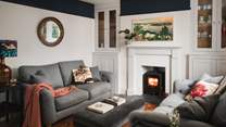 Proposing moments of fireside repose, the living area features two grey sofas arranged around a brushed velvet footstool