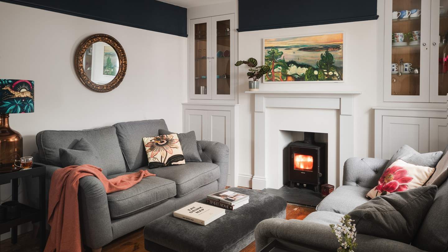 Proposing moments of fireside repose, the living area features two grey sofas arranged around a brushed velvet footstool