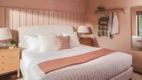 Colour drenched in soft pink tones, the first bedroom features an inviting super king size bed in boucle detailing