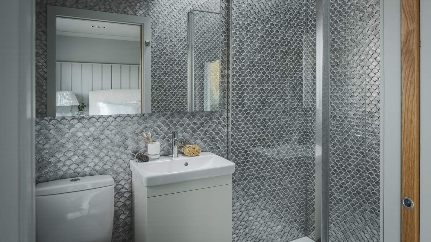 Mermaid-inspired tiles in metallic nuances offer an opulent setting for your self-care rituals 