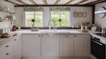 Darling exposed beams accompanying kitchen cupboards and worktops in calming hues