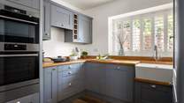 In the kitchen, sleek wooden worktops are complemented with steel finishes and a large Belfast sink