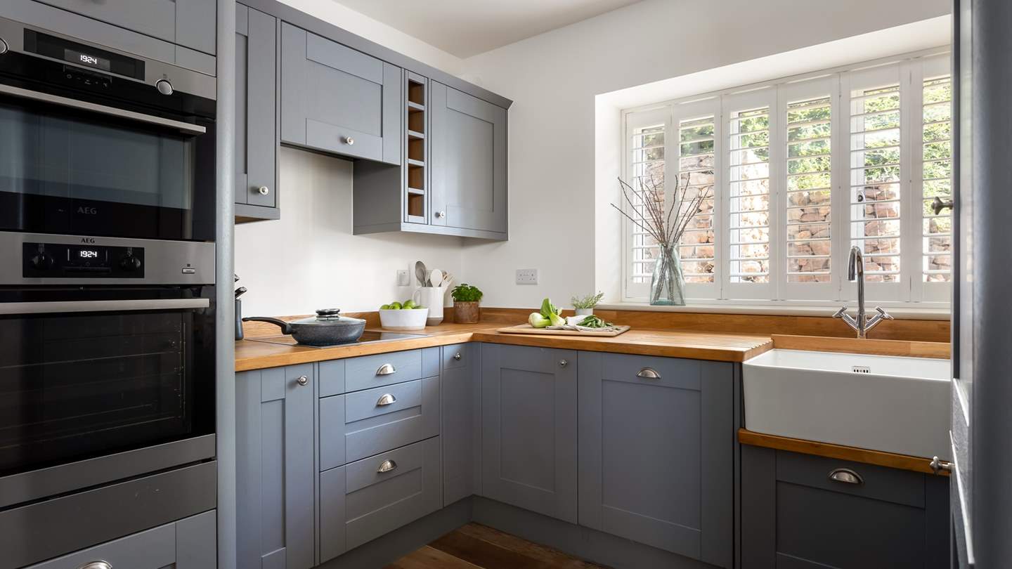 In the kitchen, sleek wooden worktops are complemented with steel finishes and a large Belfast sink