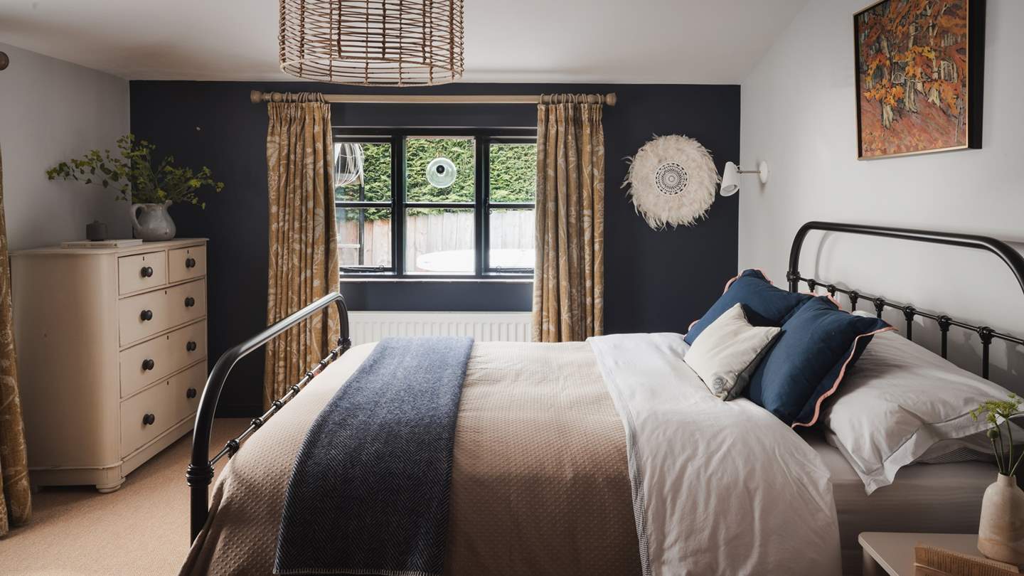 Exuding a sumptuous interior style with rich navy and mustard hues, the spacious sumptuous master bedroom is set on the ground floor