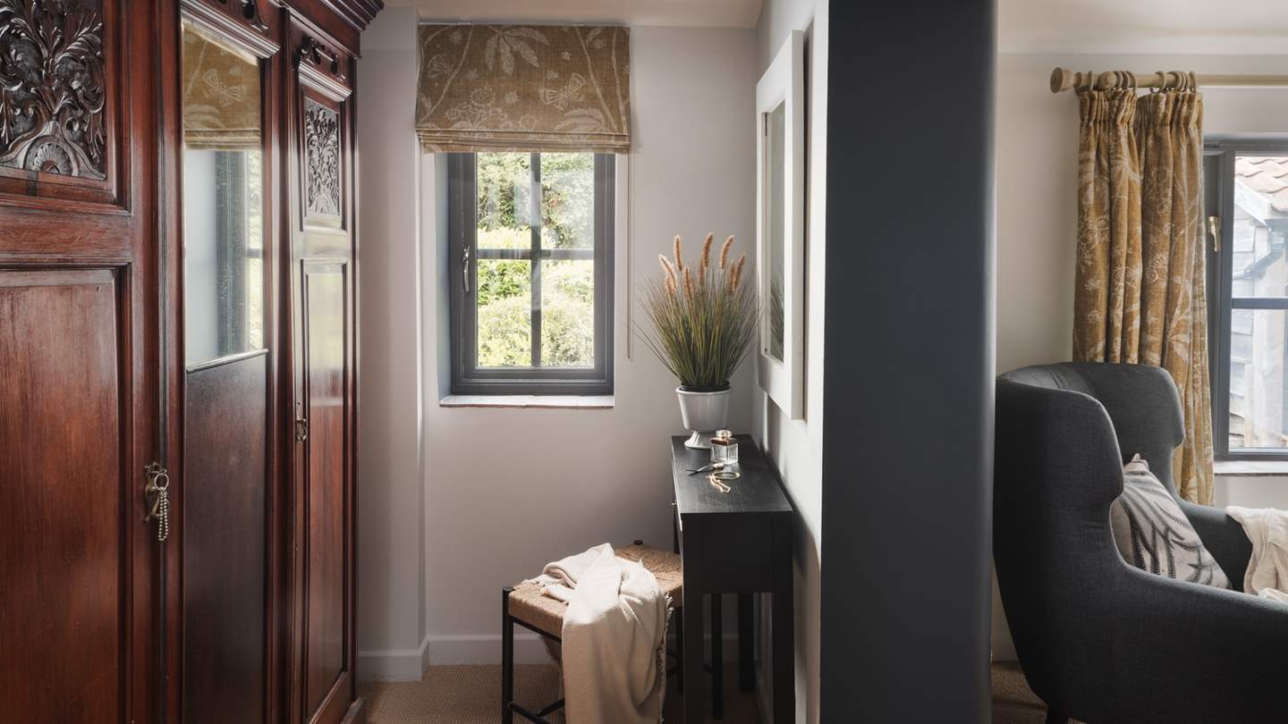 On the opposite side of the wall, lies a small dressing area, where you’ll find a stunning antique mahogany wardrobe and dressing table with stool