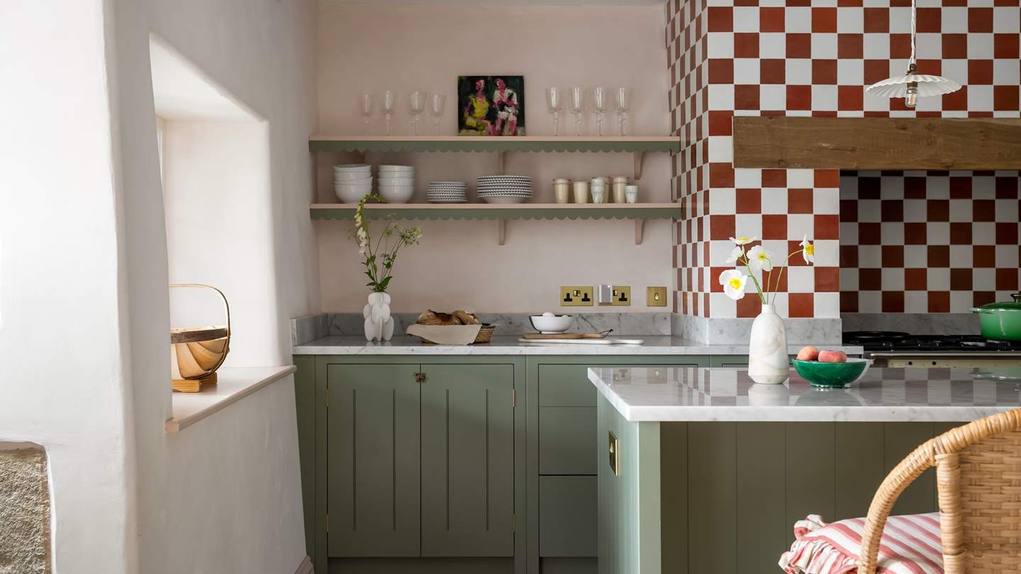 A marble topped kitchen island rests centre, set beneath pleated pendant lights