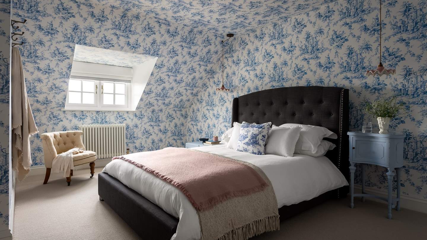 A luxe space to reside, the second bedroom promises walls adorned with elegant blue Toille de Jouy wallpaper by Jane Clayton