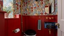 With sumptuous crimson-red wood panelling is the downstairs WC, featuring a Victorian-inspired wash basin 