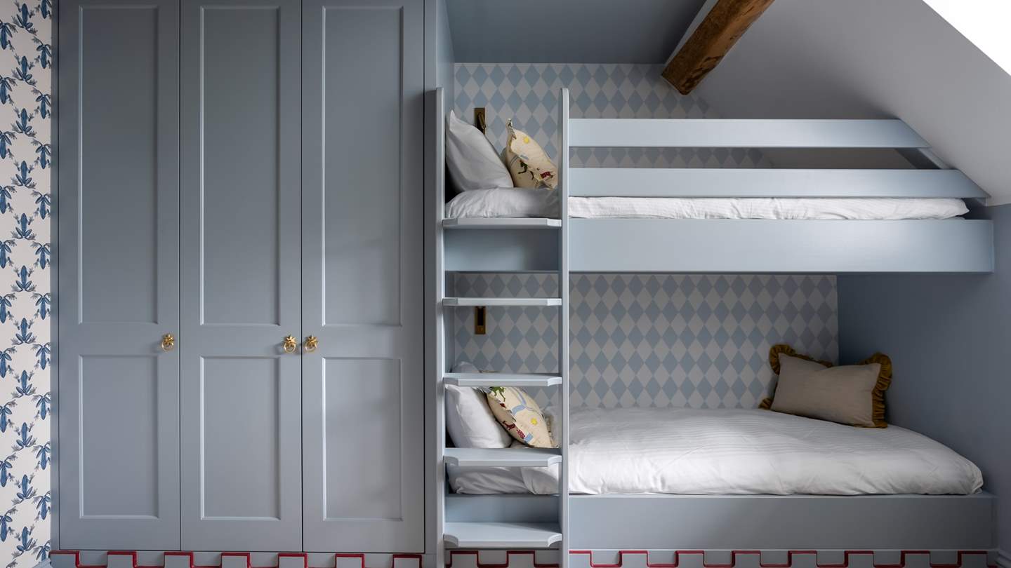 With soothing blue tones and a harlequin wallpaper feature wall, this a dreamy space for the little ones