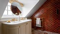 The en suite is complete with a quarry-tiled walk-in shower and a brass rainfall head
