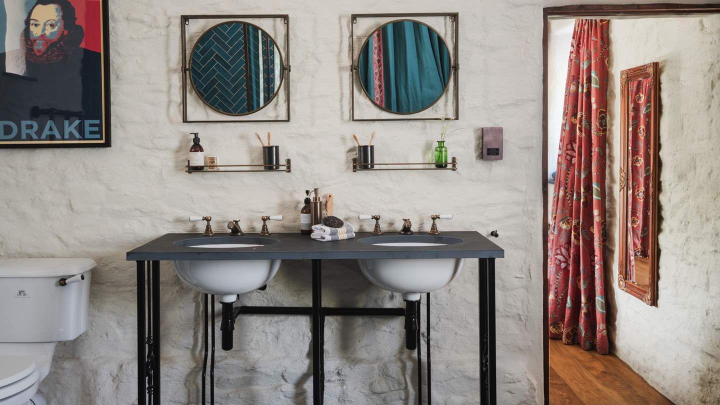 The bathroom is finished with twin sinks and embellished through industrial-edged décor