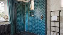 A walk-in shower with rainfall shower head awaits, with herringbone tiles in a striking turquoise tone
