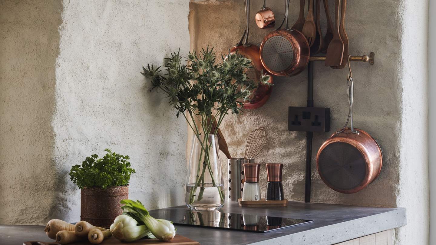 Complementing the off-white painted stone walls are an array of copper fittings and accoutrements