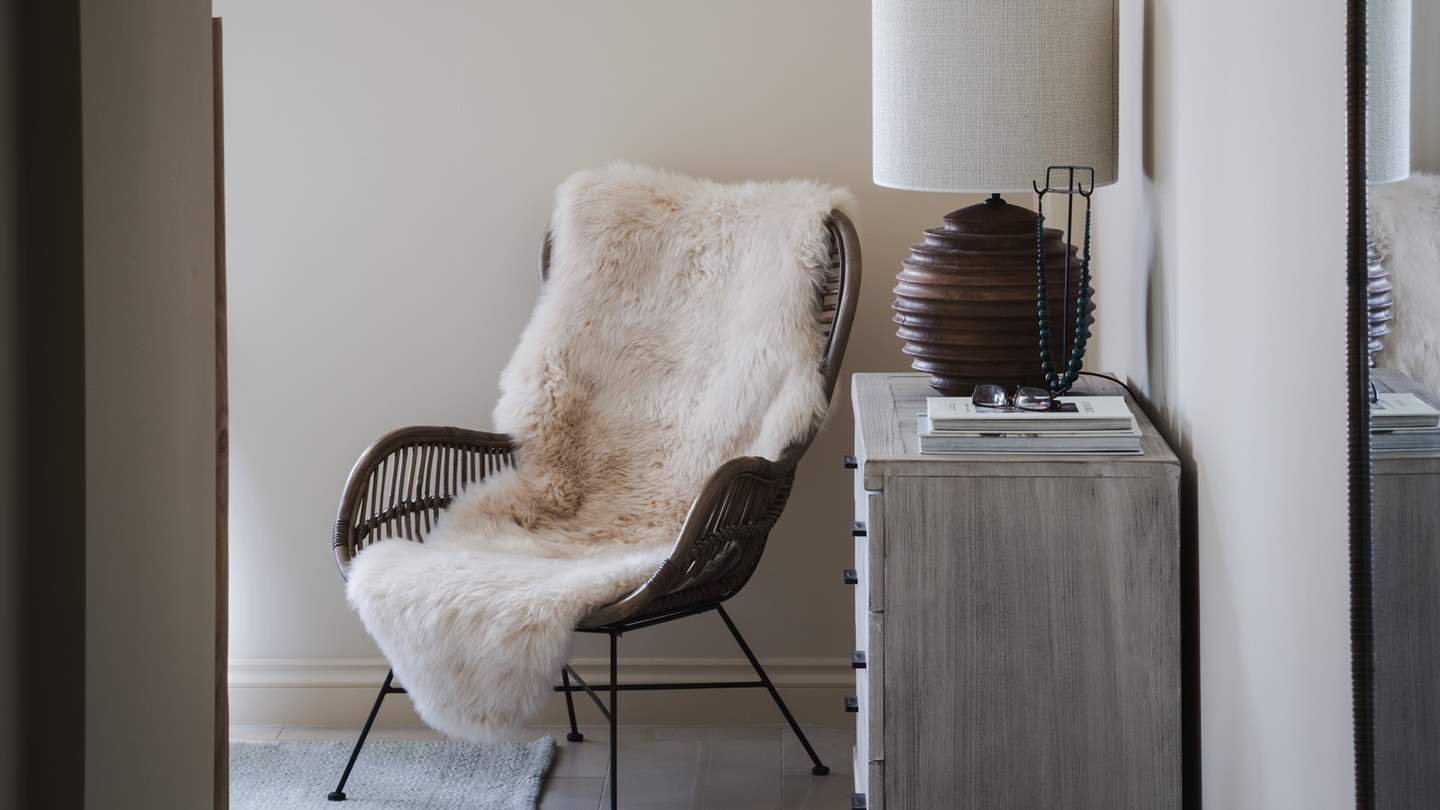 For a peaceful spot to recline, an armchair draped in soft sheepskin overlooks the garden