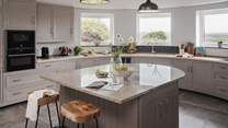 Gently arching kitchen cabinetry with garden-view windows proposes somewhere idyllic to craft repasts