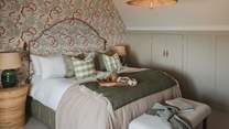 For serene slumbers, a king size bed is swathed in luxury linens and topped with cosy pillows and throws