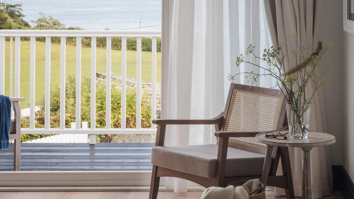 An armchair rests beside the window, and on the other side of the room, built-in wardrobes await for storing belongings