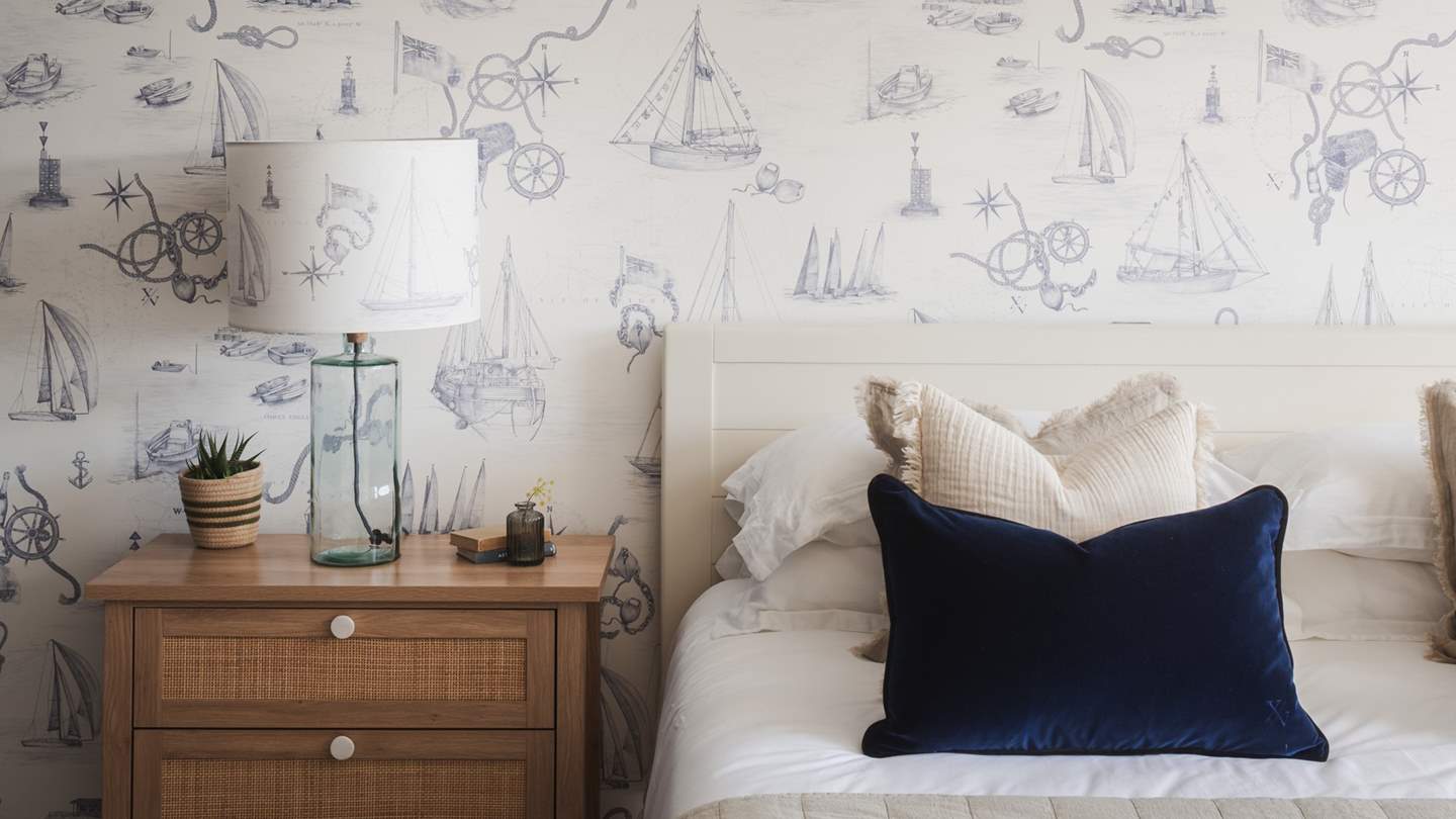 Twin rattan bedside tables sit either side of a super-king bed, swathed in the highest quality linens