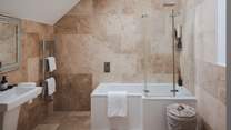 The third and fourth bedrooms share a family bathroom decorated with terracotta tiles and complete with a bath with an overhead shower