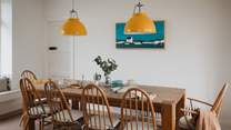 Statement lamps illuminate the farmhouse dining table, while coastal artwork reflects the waterside setting of our beautiful abode
