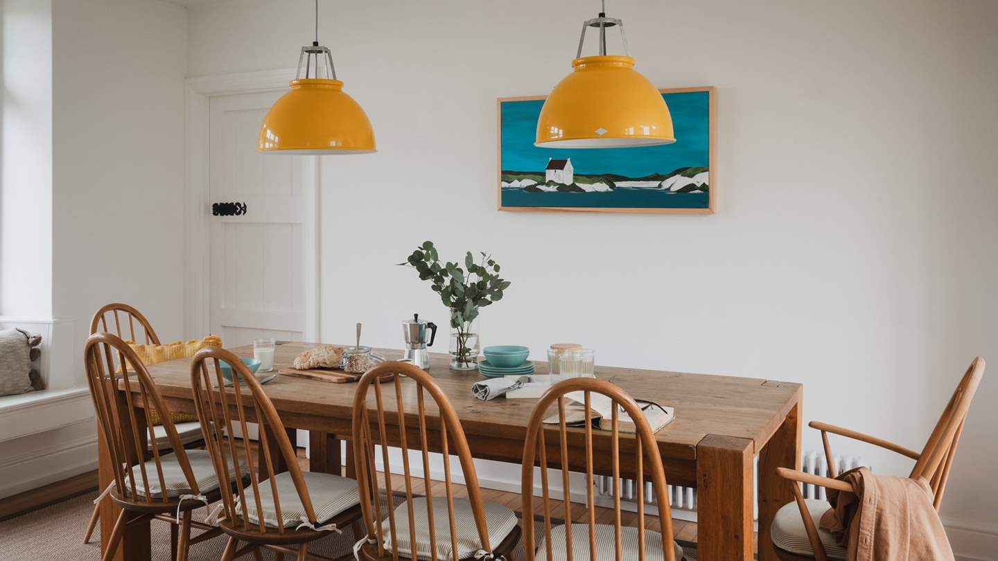 Statement lamps illuminate the farmhouse dining table, while coastal artwork reflects the waterside setting of our beautiful abode