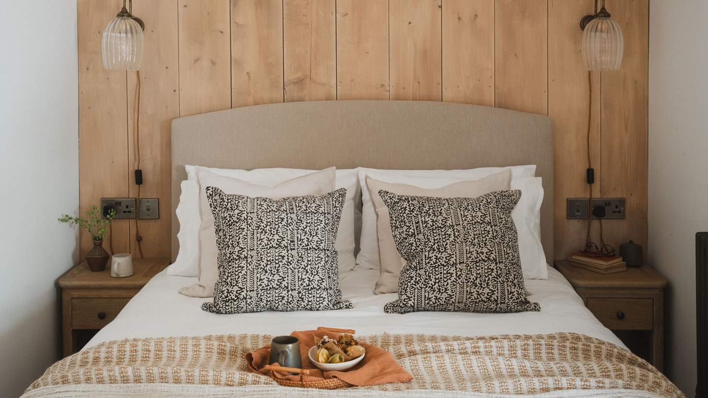 Residing in a private nook adjoining the open-plan living area, the bedroom exudes comfort and charm