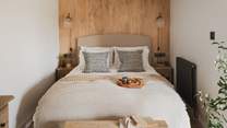 Wooden panelling with Jim Lawrence antique fluted wall lights frames a king size bed, complemented with Loaf bedside tables and terracotta lamps