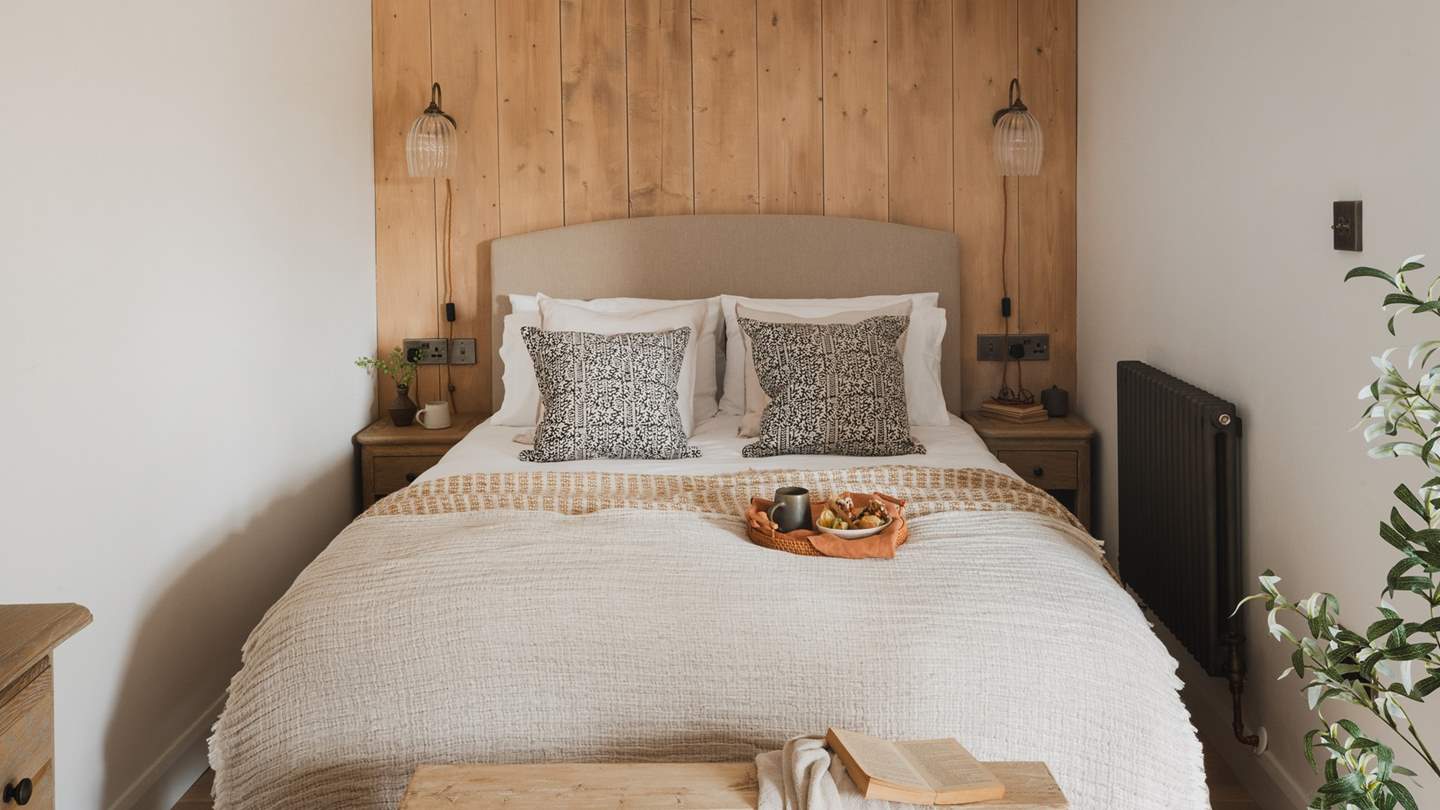 Wooden panelling with Jim Lawrence antique fluted wall lights frames a king size bed, complemented with Loaf bedside tables and terracotta lamps