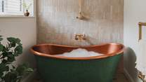 Promising the dreamiest soaks is a large, freestanding copper bath in shades of verdigris green, complete with an overhead shower
