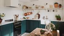 The kitchen features handcrafted, evergreen cabinetry harmonised with antique brass details and a quartz worktop