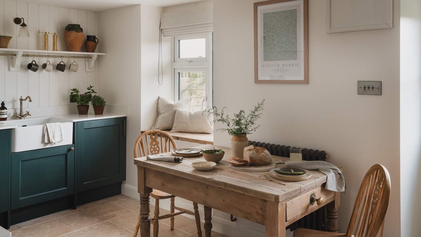 For romantic repasts, an antique farmhouse table is embraced by two wood dining chairs and illuminated by antique brass lights