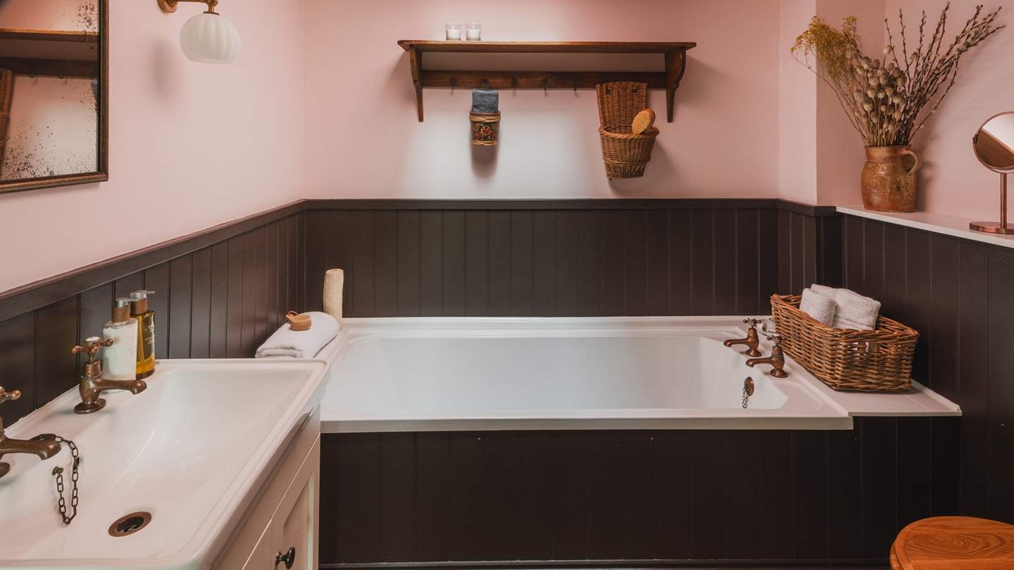 Featuring reclaimed terracotta tiles, black wood panelling and powder pink walls, the bathroom at Beira’s Glen is effortlessly romantic