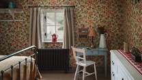This pretty space is swathed in Strawberry Tree wallpaper by Cole & Son and adorned with frilled wall sconces