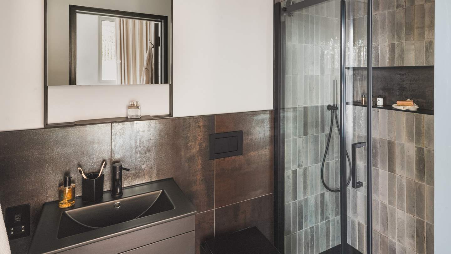 This bedroom enjoys its own bathroom with patinated tiles and a spacious walk-in shower
