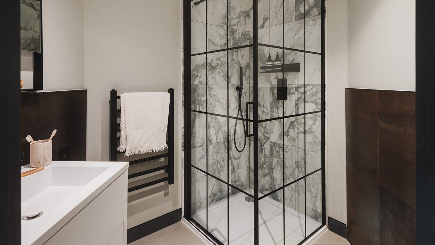 This bedroom features an ensuite with a chic industrial style walk-in shower