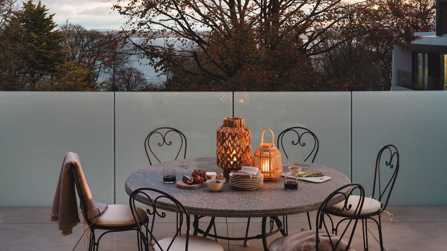 Sliding patio doors reveal an ocean-view balcony with an outdoor bistro set for alfresco dining