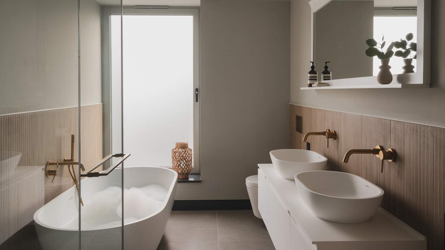 An elegant freestanding bathtub beckons for bubble-topped soaks