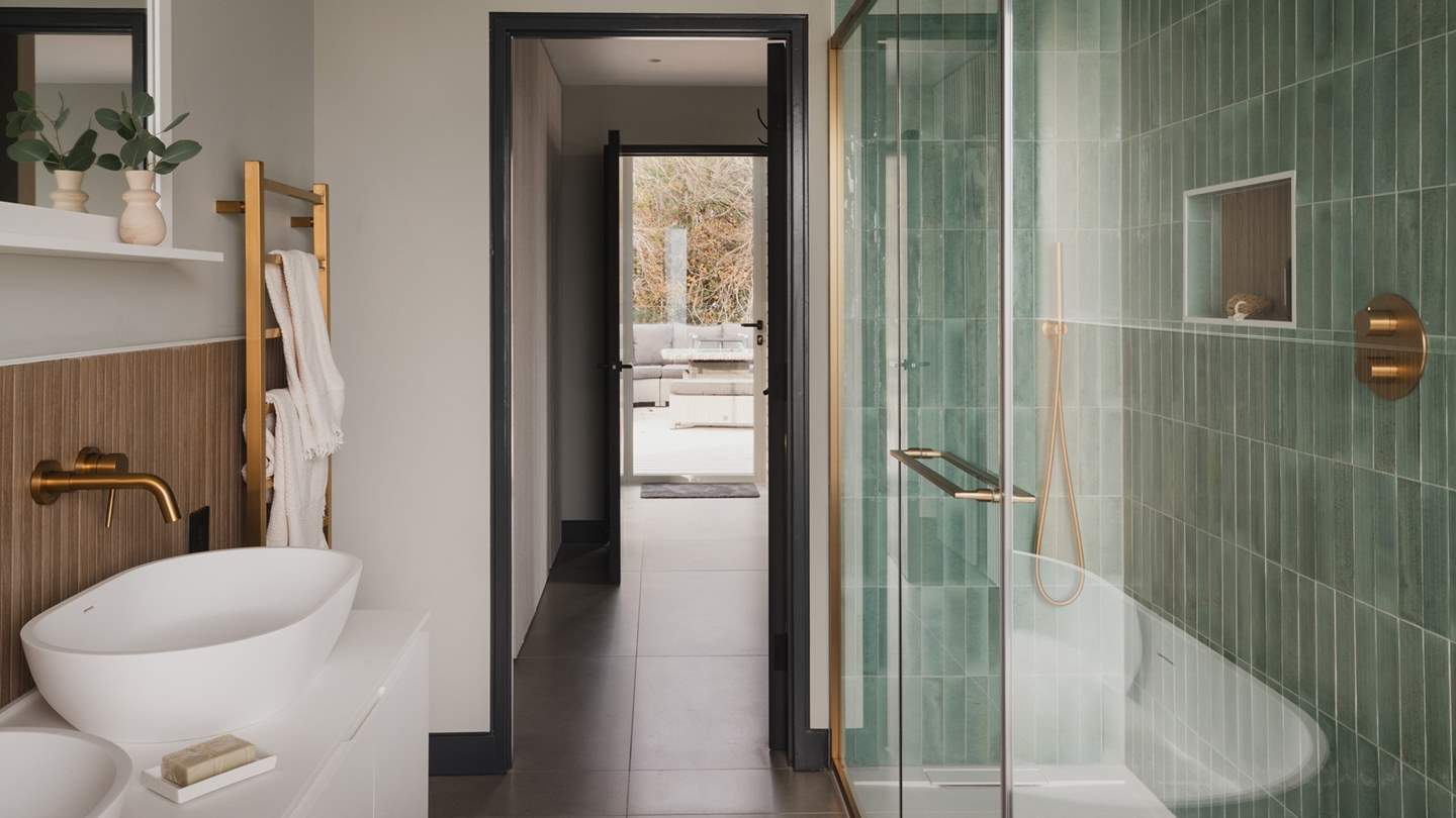 This room is complete with an ensuite bathroom, where turquoise tiles and organic inflections frame a walk-in shower