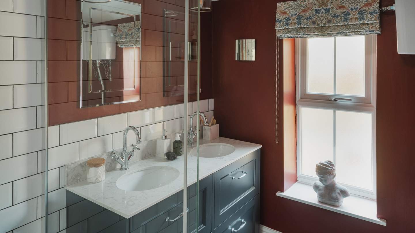 The bespoke dual vanity complements the rich rouged walls beautifully