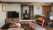 The living room radiates cosiness, with low ceilings and exposed beams adding rustic touches to this charming space