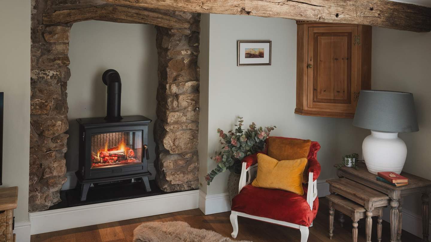 An electric wood-effect stove sits within an exposed stone feature fireplace and hearth, promising warmth to your evenings 