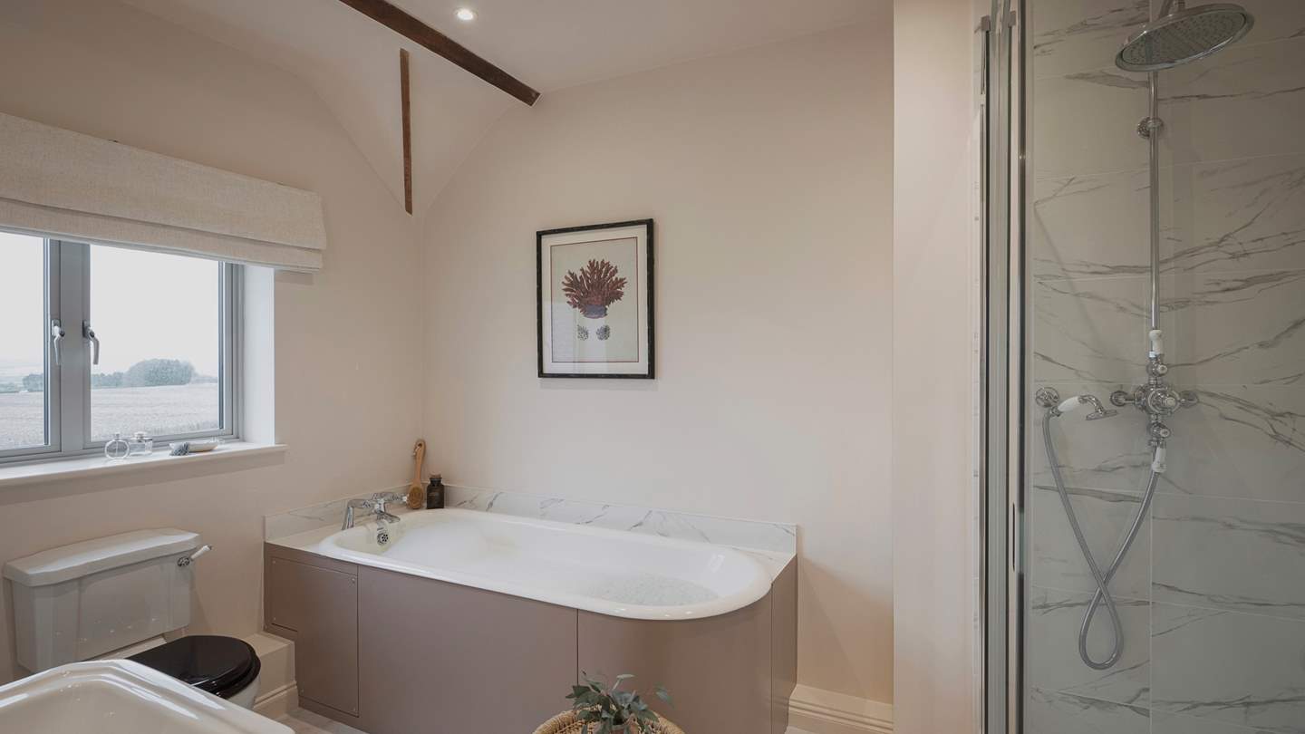 This bedroom has an ensuite bathroom for privacy and comfort, complete with a walk-in shower and a bath for serene soaks