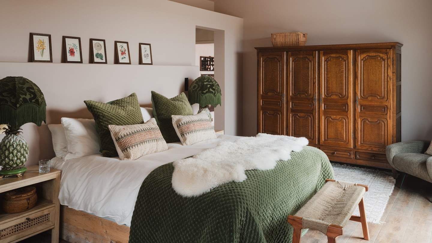 Muted pink walls contrast perfectly with forest green accents in the romantic master bedroom